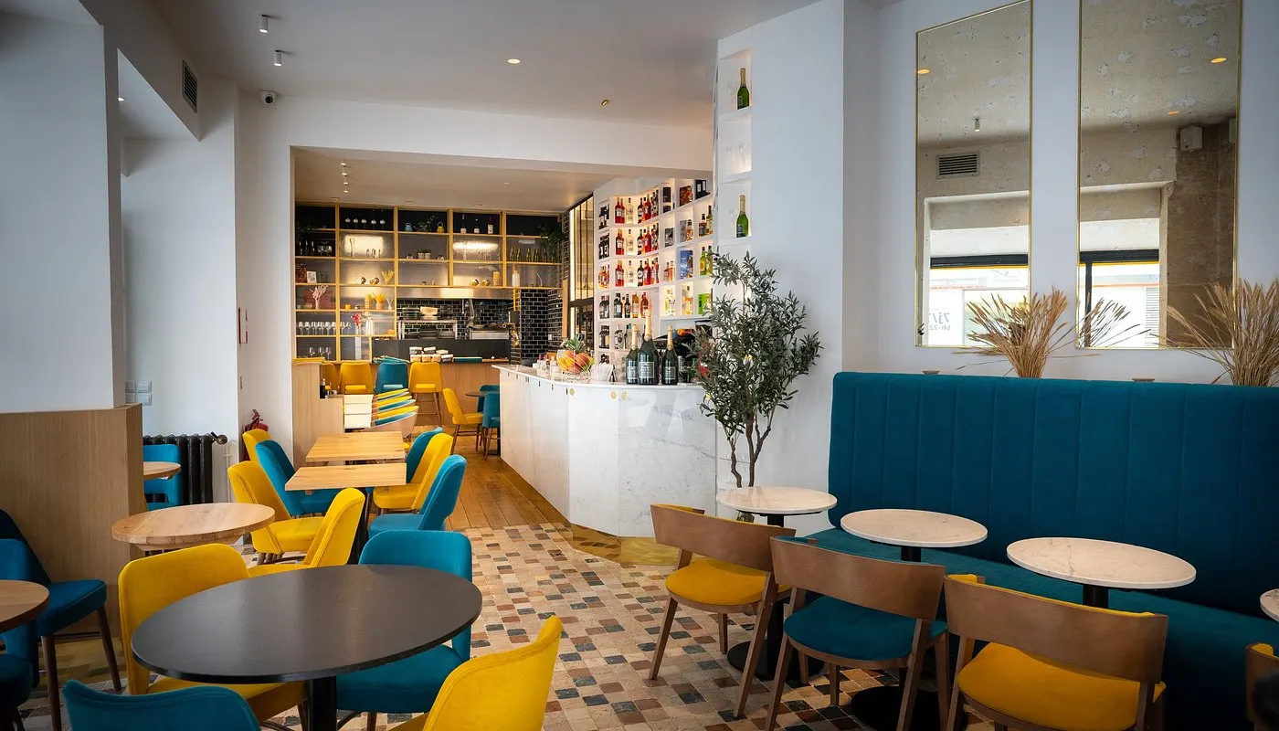 La salle de Perlamatta, chaises jaunes, banquette bleue et carreaux de ciment
